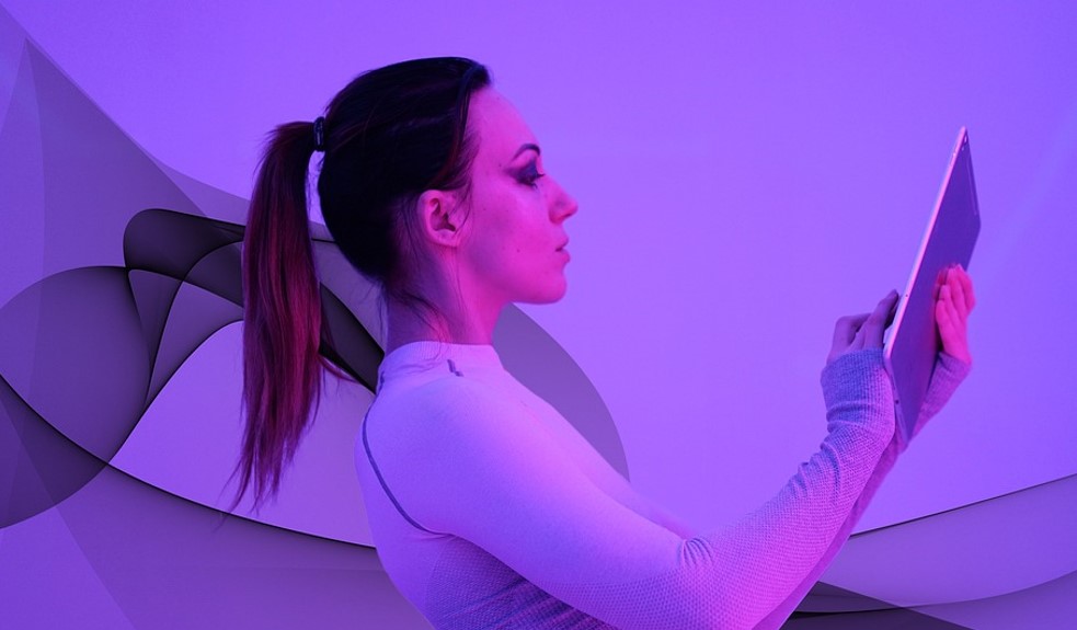Woman using computer tablet; futuristic neon purple light